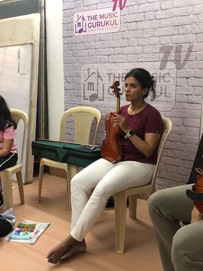 A violin group class in session. Students are learning the fundamentals of holding the instrument and bow correctly, which is crucial for developing good habits and a beautiful tone.