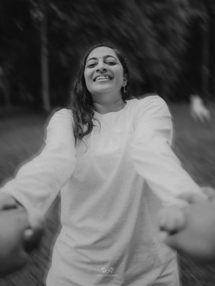 A joyful black and white shot from the groom's perspective, holding the bride's hands as she smiles.