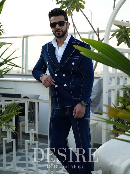 This blue velvet suit is designed to make a statement. The double-breasted cut and contrast piping create a look that is both bold and sophisticated.