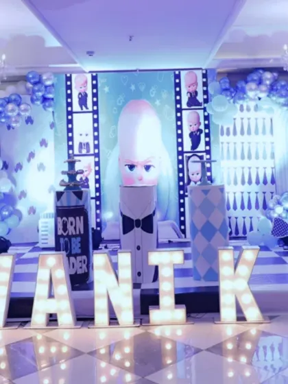 A 'Boss Baby' theme is perfect for a first birthday. This grand setup for Swanik's party included large marquee letters spelling out his name, a custom backdrop with character cutouts, and a blue and white balloon arrangement to complete the corporate-cool look.