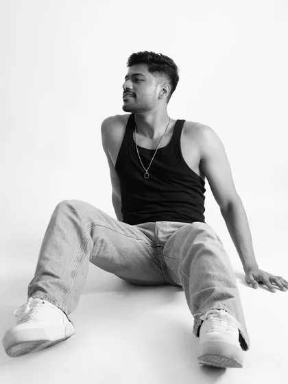 A relaxed, seated black and white portrait in a studio. Even in a casual pose, this shot effectively highlights the model's athletic build in a clean, professional setting.