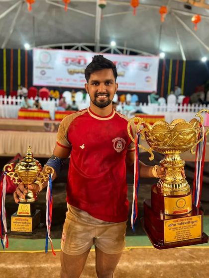 A smiling Raj Natekar holding his two trophies after a successful tournament.