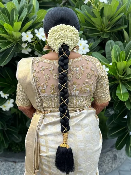 A simple yet elegant traditional braid, crisscrossed with gold ribbon and topped with a beautiful jasmine gajra.