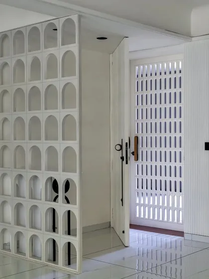 A pivoting screen with arched cutouts acts as a dynamic partition, allowing for both privacy and openness.