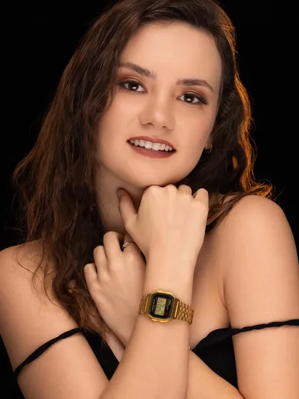 A classic beauty portrait of a model with warm lighting against a black background, showcasing her flawless makeup and serene expression.