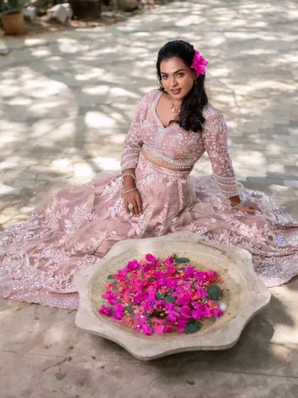 A creative shot from a model shoot, with the model sitting by a bowl of bougainvillea flowers, adding a pop of color to the scene.