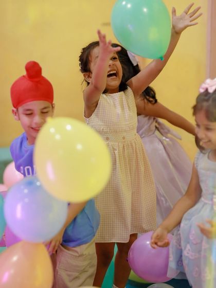 A young girl laughs with pure joy as she plays in a sea of colorful balloons. Simple fun often creates the best memories.