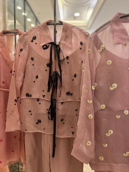 Sheer elegance stitched with floral dreams. This organza co-ord set features a delicate shirt with a black ribbon tie and scattered floral embroidery.