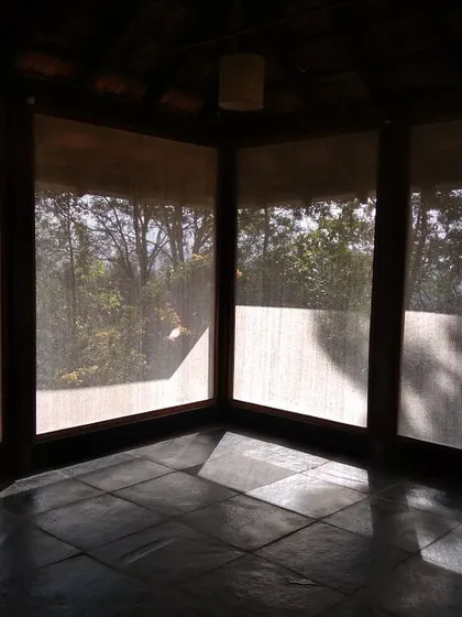 The interior of the yoga pavilion, a calm and simple space with large windows that look out onto the blue mountains of the Nilgiris.