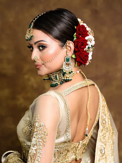 A detailed look at a classic bridal hairstyle. This intricate floral bun, featuring fresh red roses, is a timeless choice that provides an elegant and secure foundation for the bridal dupatta.