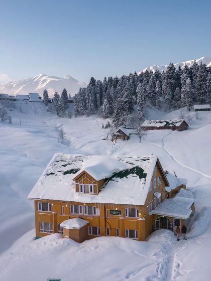 A photo of a beautiful, snow-covered hotel in Gulmarg, Kashmir, capturing the magical winter scenery of the valley.