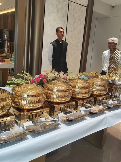 Our full-service catering is designed so you don't have to lift a finger. We provide an elegant and professional buffet setup, complete with these beautiful gold-finish chafing dishes to keep food warm, all the necessary crockery, and our trained, uniformed staff to manage the service.