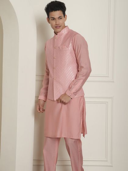 A pink kurta pajama set with a matching textured jacket. This is a great option for a day event, offering a soft yet stylish look.