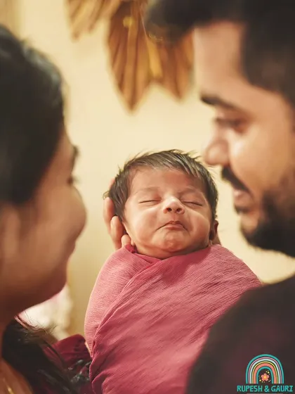 The purest love. A close-up of parents gazing at their newborn, who has a tiny, content smile. These are the moments that truly matter.