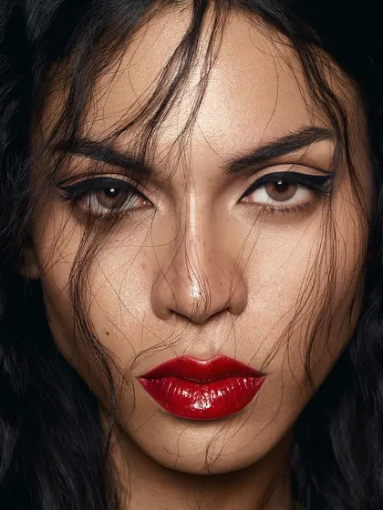An intense and direct beauty portrait that embodies our 'clean but glam' philosophy. The focus is on the flawless skin, the piercing gaze, and the perfectly executed glossy red lip, creating a timeless yet modern editorial image.