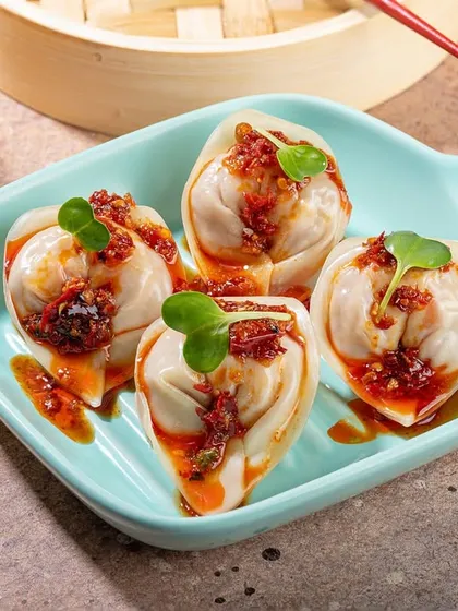 Artfully plated dim sum with a spicy chili topping. The bright, modern plate and focused lighting make this a great shot for a contemporary Asian restaurant.