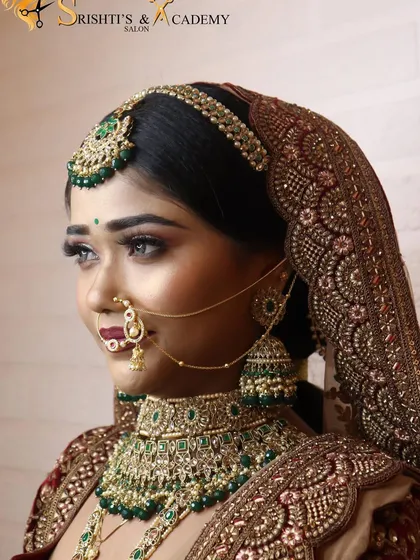 A close-up profile of a royal bridal look, emphasizing the intricate details of the matha patti, nath, and layered necklaces.