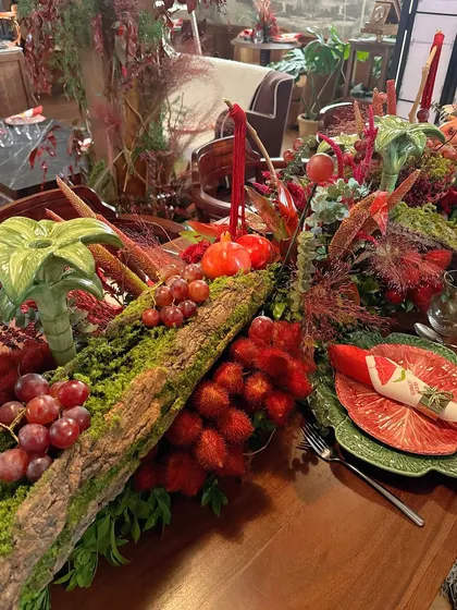 A lavish, rustic tablescape for the Scarlett House launch party. A moss-covered log acts as a runner, overflowing with red flowers, grapes, and pomegranates.