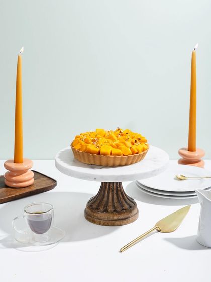 Our Mango Tart, beautifully styled with candles, ready for an elegant dessert course.
