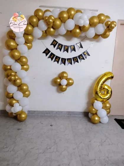 A classic gold and white balloon arch for a 6th birthday party at home.