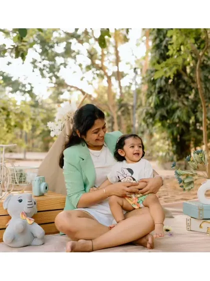 A mother and her child share a quiet, happy moment during an outdoor picnic setup. The soft lighting and relaxed pose create a feeling of warmth and contentment.