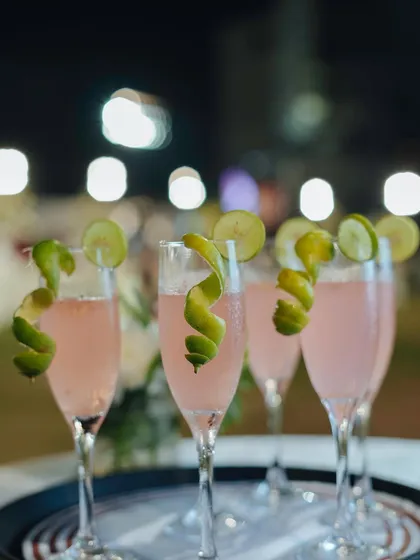 A beautiful pink mocktail served in a champagne flute with a lime twist. Our drinks are designed to add a touch of celebration to your event.