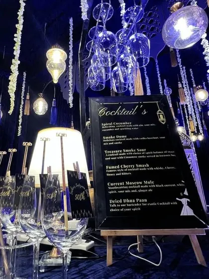 For a sophisticated Sufi night, I designed this elegant bar with deep blue tones, hanging lights, and a custom menu for a 50th celebration.