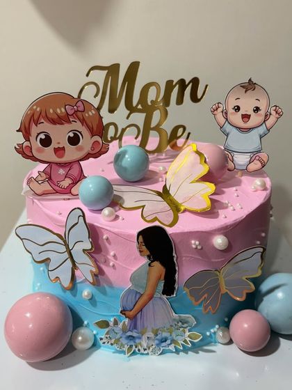 Another look at the adorable baby shower cake, decorated with cute baby toppers, butterflies, and chocolate spheres.