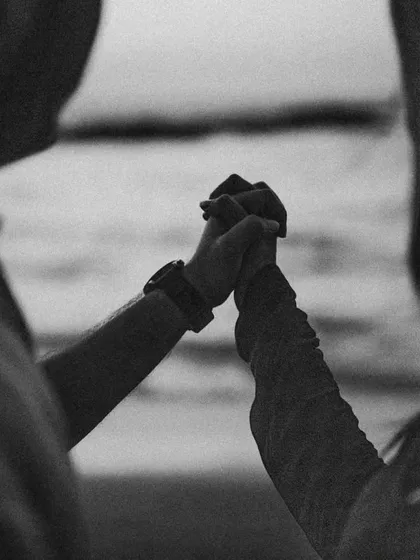 A black and white detail shot of a couple holding hands, with the Goan sea in the background. Sometimes the simplest gestures tell the most powerful stories of love and commitment.