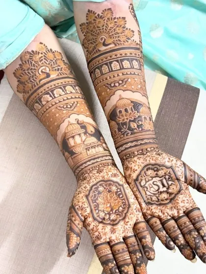 This design features peacocks and palace architecture, with the bride's name, "RASI", and her groom's initial integrated into the palms.
