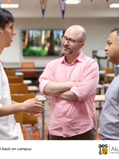 An alumnus back on campus speaks with faculty members. We encourage our graduates to return, share their experiences, and mentor current students, strengthening the university guidance process.
