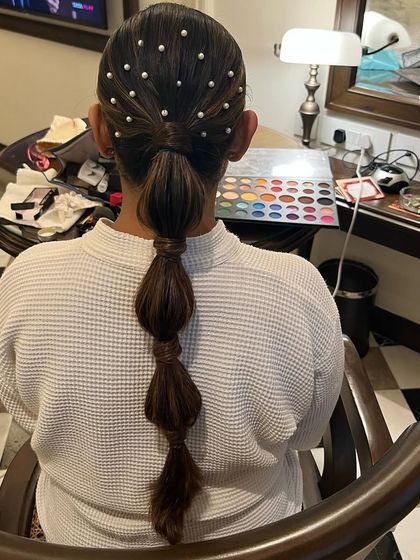 A sleek and modern bubble ponytail, with the top section adorned with scattered pearls for a chic and trendy vibe.