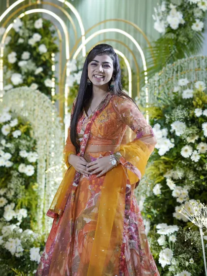 A real candid from a recent event, standing against a beautiful floral backdrop.