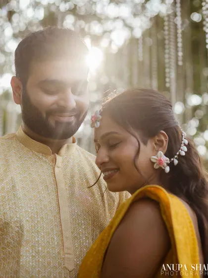 A soft, dreamy portrait of the couple bathed in beautiful backlight. The sun creates a gentle flare, adding a romantic and ethereal quality to this Haldi moment.