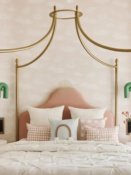A close-up of the dreamy canopy bed with a pink velvet headboard. We layered cute pillows with rainbows and gingham patterns to add personality and fun.