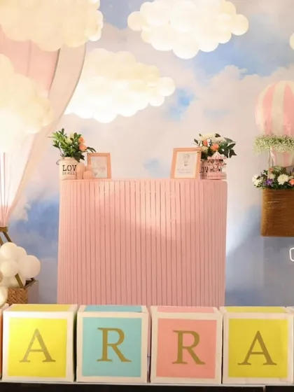 A closer view of the hot air balloon party dessert station. A teddy bear sits on the custom name blocks, and a basket with flowers hangs from a balloon.