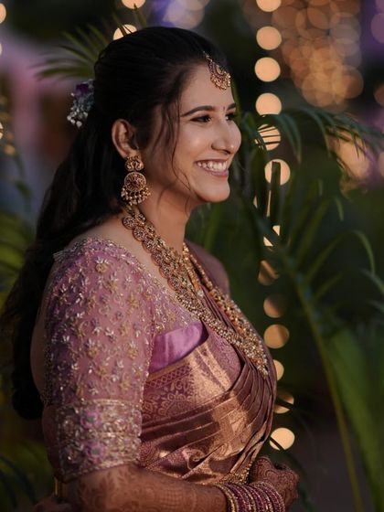 A beautiful photo with bokeh lights, highlighting the bride's joyful expression and the intricate beadwork on her custom blouse.