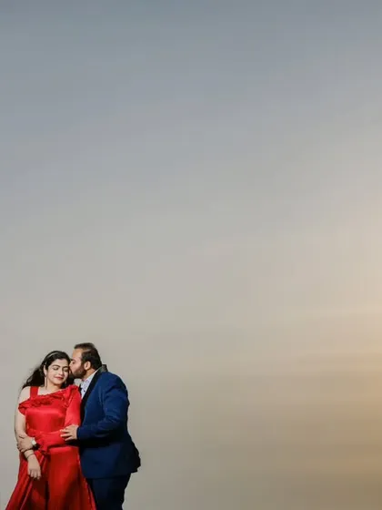 A minimalist pre-wedding photo with a beautiful lens flare from the sun. The composition uses negative space to draw the eye directly to the couple's affectionate embrace.
