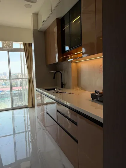 A side profile of the kitchen, showing the depth of the counters and the natural light coming from the large window. The black sink and faucet complement the cabinet handles.