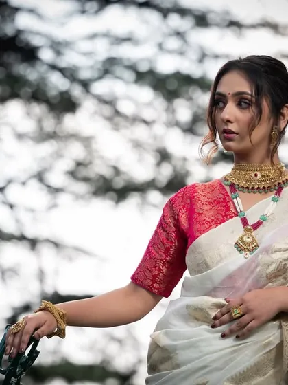 A classic portrait pose, with the model's hand resting on the railing, showcasing the full set of traditional jewelry.