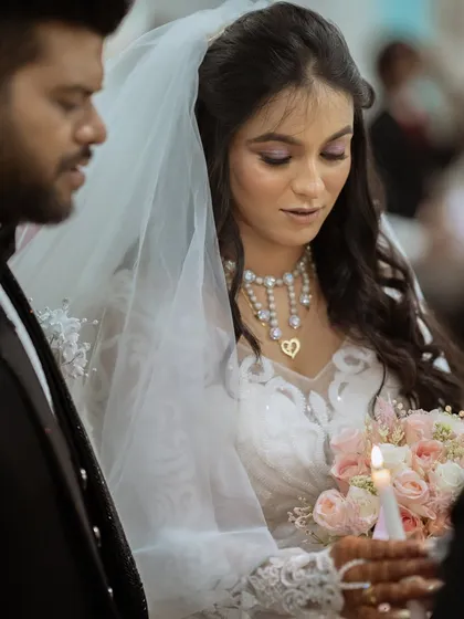 A solemn moment during the church ceremony, with the bride holding a candle.