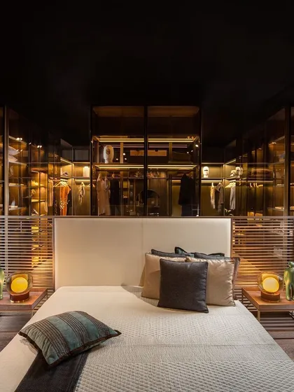 Here, I've used a see-through island wardrobe to create a subtle partition between the sleeping and dressing areas. This approach opens up the bedroom, merging the two spaces into one grand suite while showcasing your finest pieces like works of art.