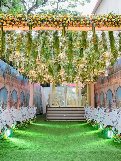 We created this immersive Pichwai-themed entrance for an event at Hiravati Banquet. The walkway is lined with custom cow cutouts against a backdrop of traditional Rajasthani art, while the ceiling is adorned with hanging floral arrangements and golden birdcages, guiding guests into a magical space.