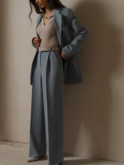 A dusty blue suit styled with a neutral ribbed top and belt. The wide-leg, pleated trousers create a relaxed yet sophisticated look.