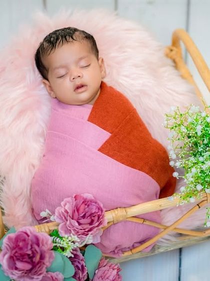 A slightly different angle of the pink and orange wrap session, showing how I can capture multiple beautiful shots from a single setup. The baby is resting peacefully in a basket lined with soft fur.