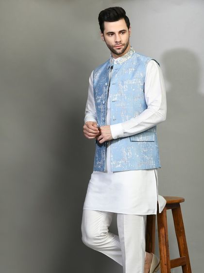A cool and calming combination of a white kurta with a powder blue printed jacket. This is an ideal choice for a daytime event or a destination wedding.