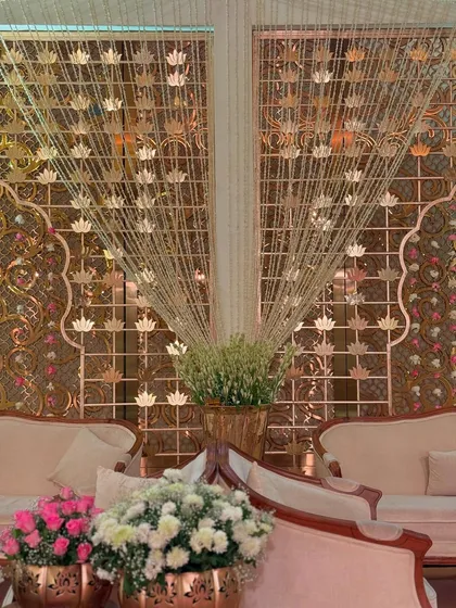 A cozy lounge area set against a backdrop of intricate golden screens and hanging floral strings. We design these spaces for comfort without compromising on luxury.