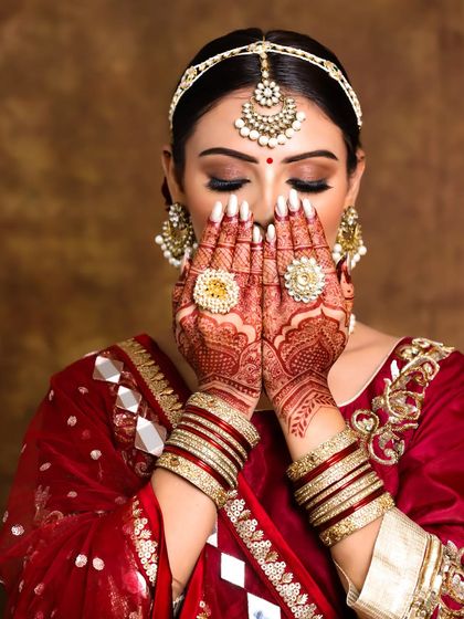 A beautiful, artistic shot of a bride's henna-adorned hands, framing her soft and elegant makeup.