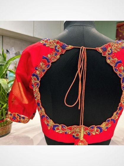 The back of the red blouse with the large circular cutout, showing the delicate tie-up and custom tassel.