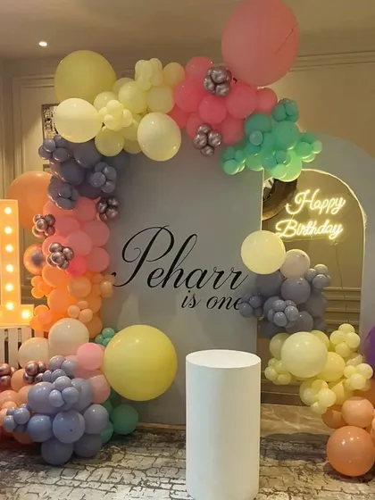 Peharr is one. We designed this beautiful and modern first birthday setup with a custom arched backdrop and a unique pastel rainbow balloon garland, creating a soft and dreamy atmosphere for the celebration.